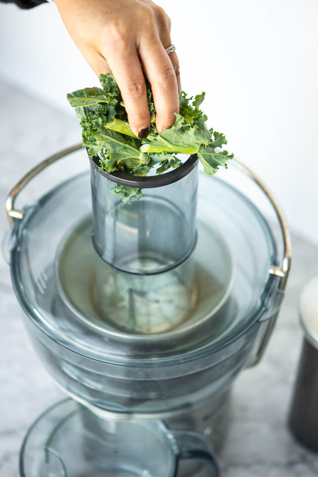 Chopped kale being put into juicer.