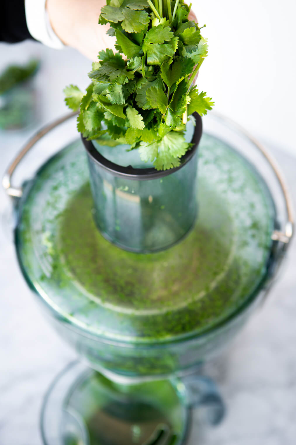 Cilantro being put into juicer.