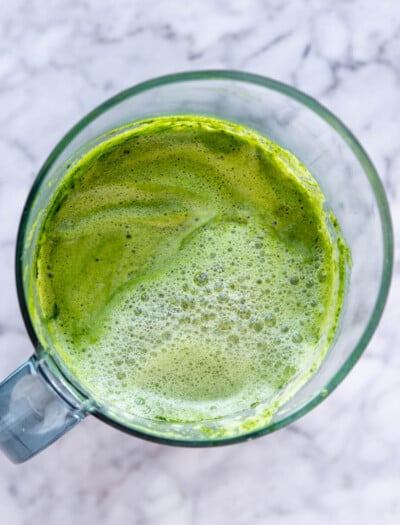 Top down view of green juice in a pitcher.