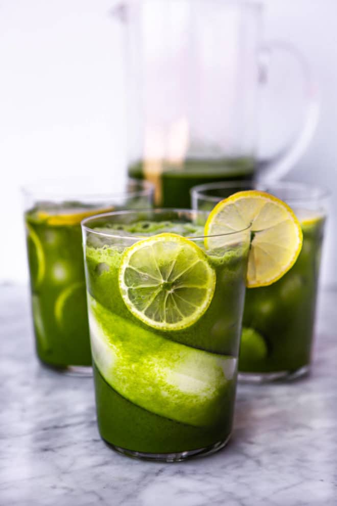 Three glasses lined with cucumber and lemon slices with ice and juice.