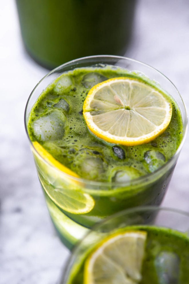 Top-side view of green juice in class topped with lemon slice.