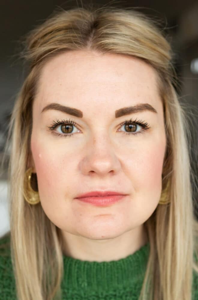 Headshot of Lauren in a Kelly green sweater not smiling wearing Honest mascara. 