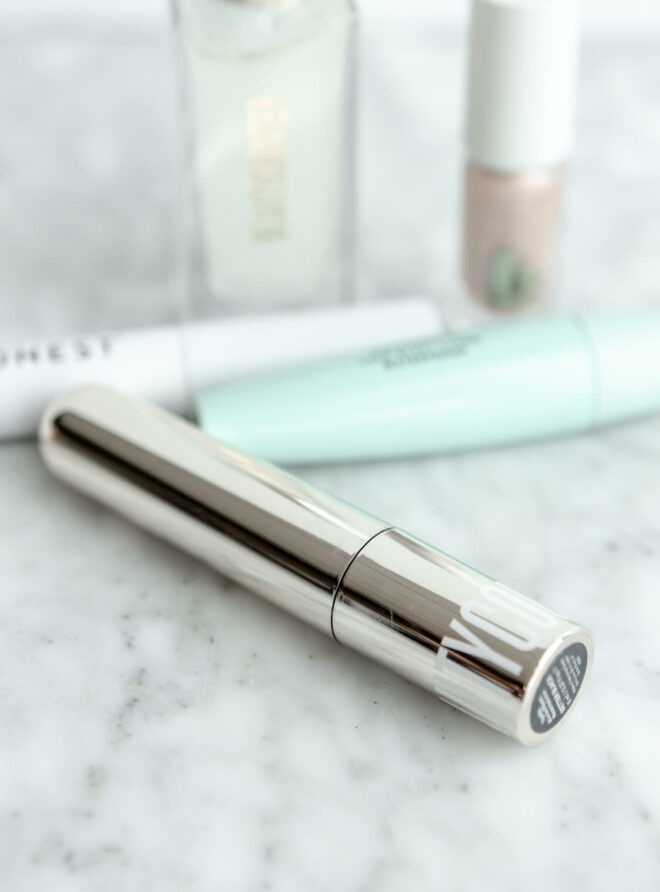 Beautycounter mascara on a gray and white marble surface with other makeup in the background.