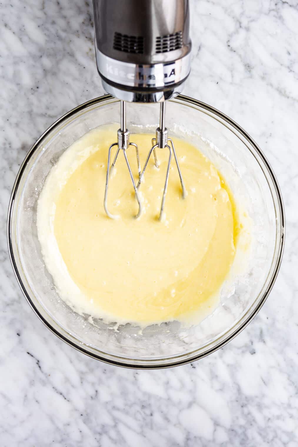 Batter in a glass bowl with hand mixer resting on the side of the bowl.