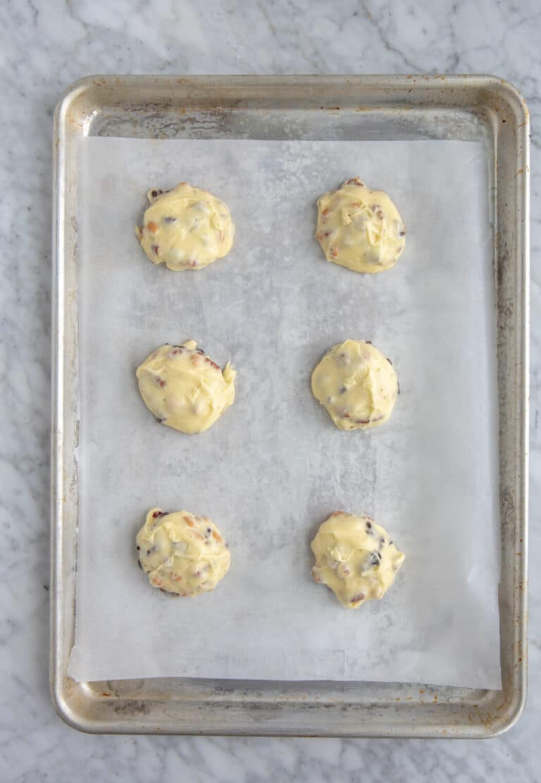 Cookie dough placed in three rows of 2 on a parchment lined baking sheet.