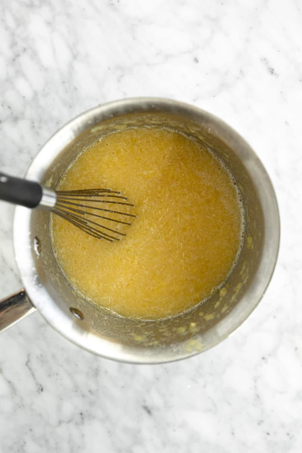 Pineapple filling in a steel saucepan with a whisk,