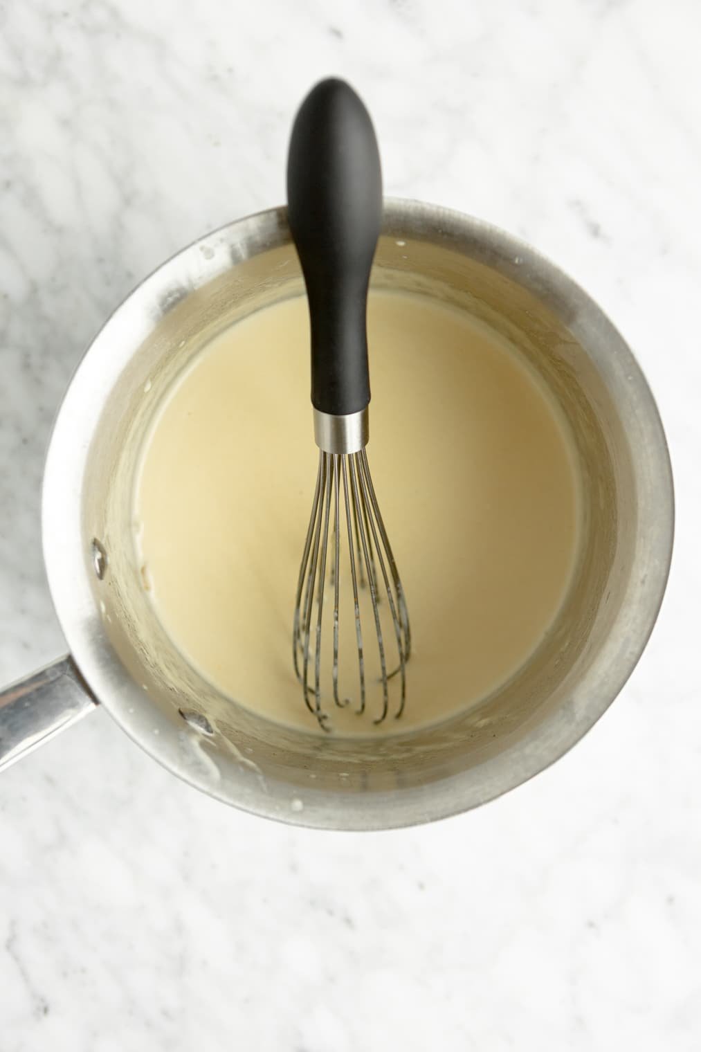 A creamy alfredo sauce in a stainless steel saucepan.