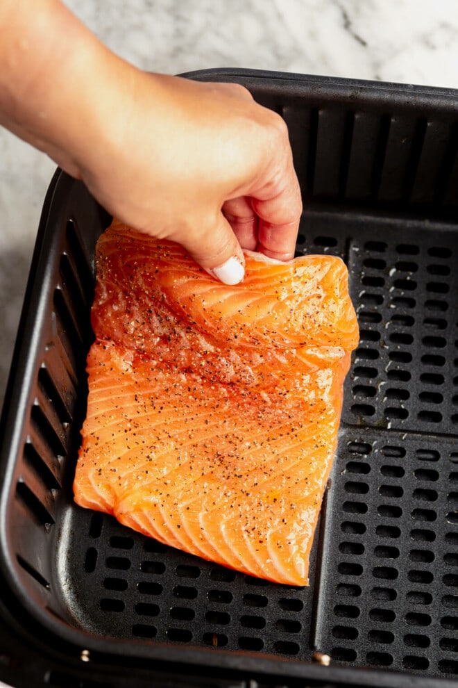 Salmon filet being placed in the air fryer.