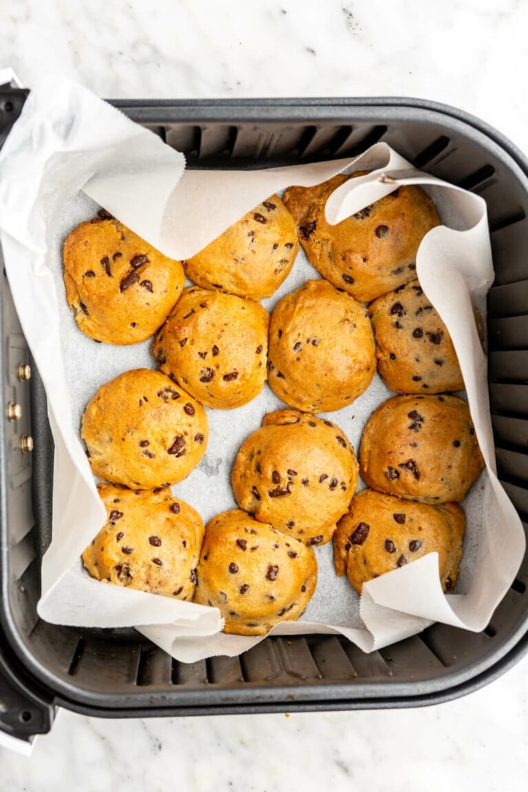 Air fryer basket lined with parchment paper with baked cookies.