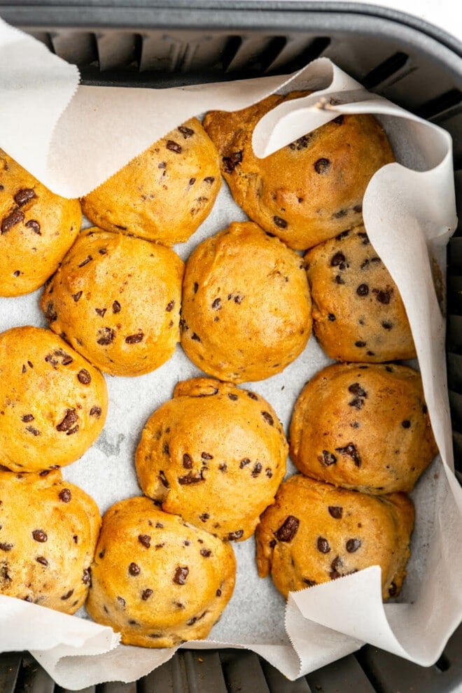 Top down view of cookies in an air fryer basket lined with parchment paper.