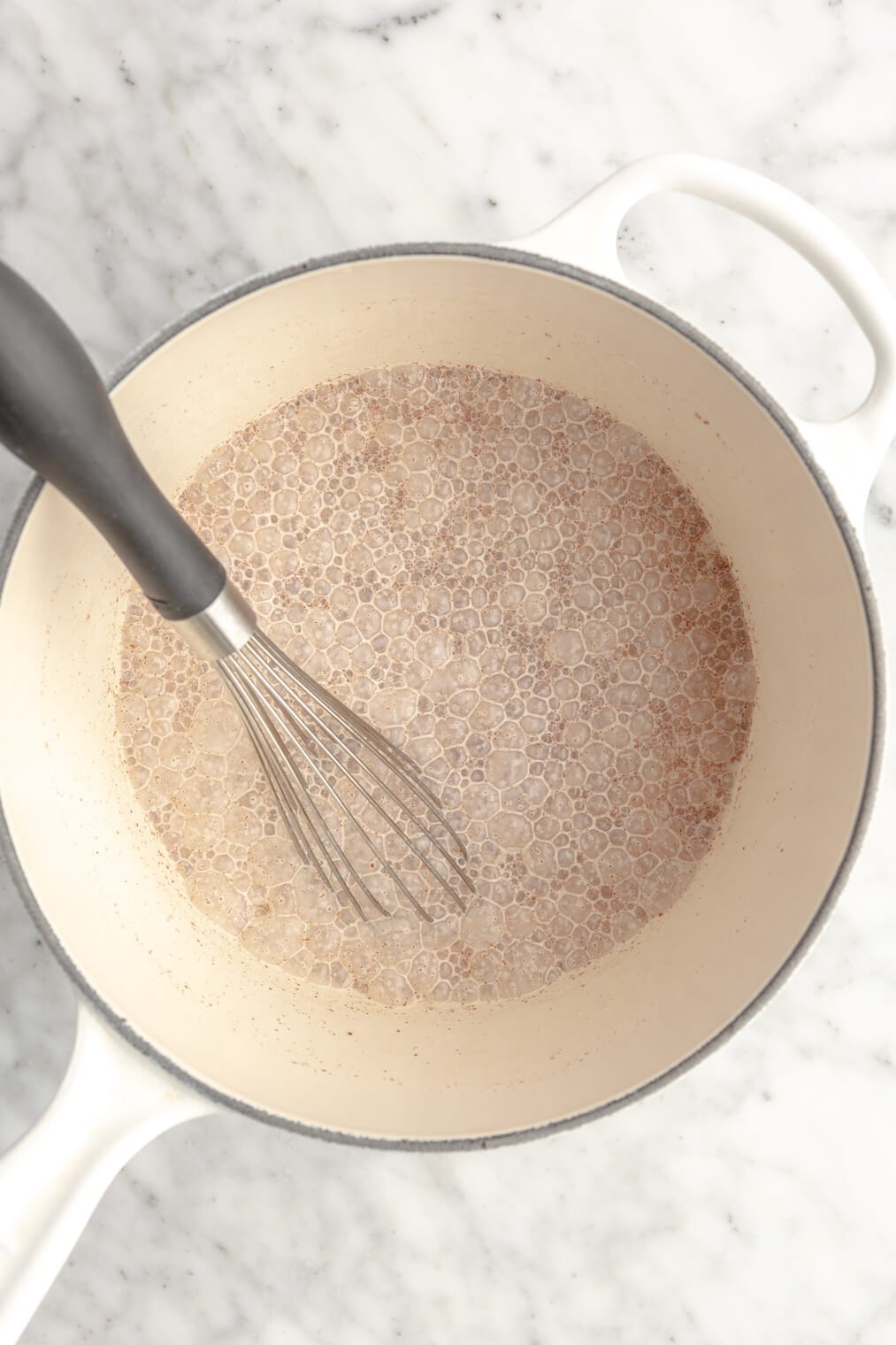 Brown sugar creamer ingredients whisked in a white saucepan.