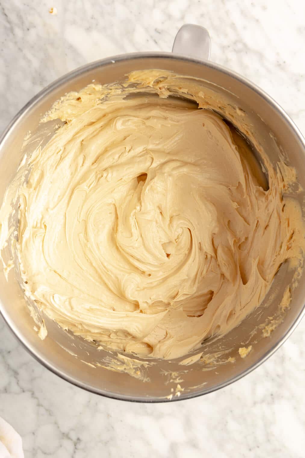 Smoothed peanut butter buttercream in a metal mixing bowl.