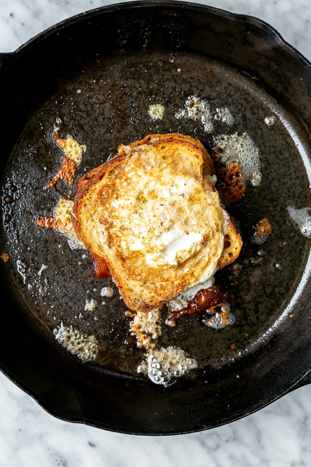 Slice of bread with egg cooked in the middle in a cast iron pan.