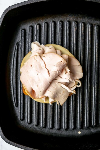 Turkey on top of a slice of bread in a cast iron grill pan.