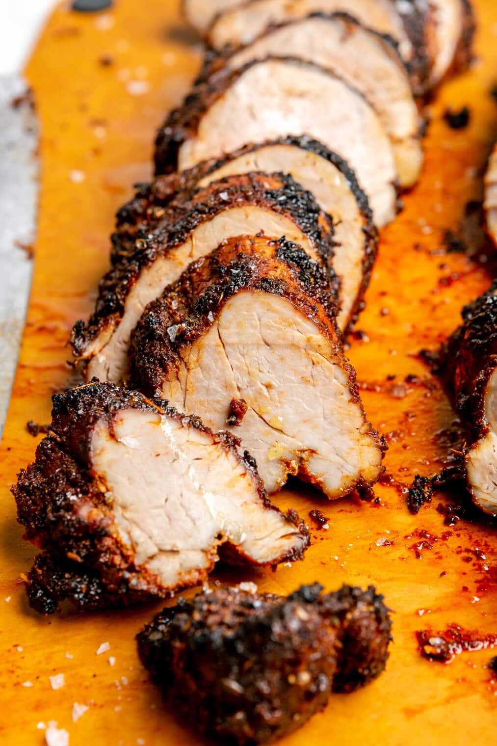 Sliced, spiced pork tenderloin on an epicurean cutting board.