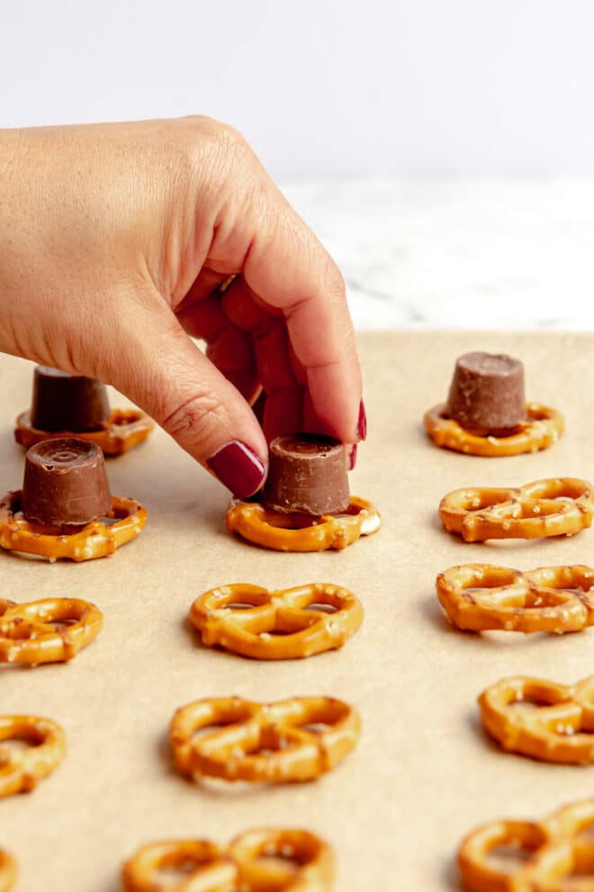 Hand topping pretzels with a rolo candy.