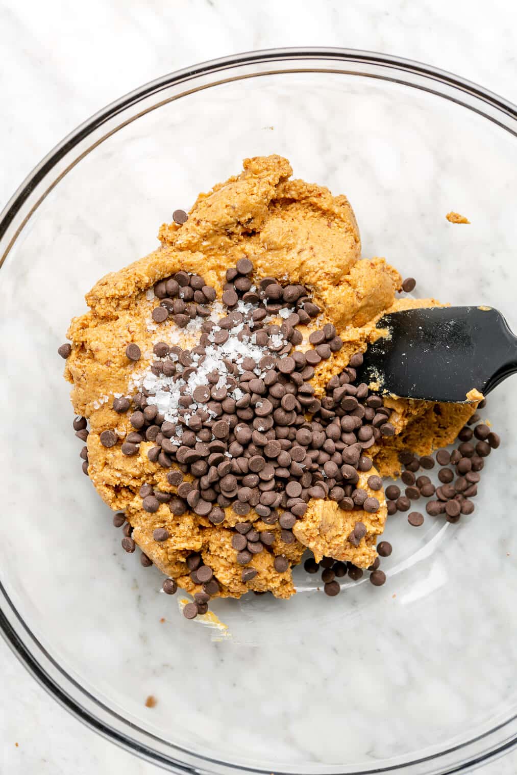 Spatula stirring chocolate chips into peanut butter ball batter.