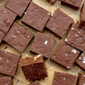 Small squares of chocolate fudge on a brown piece of parchment paper.