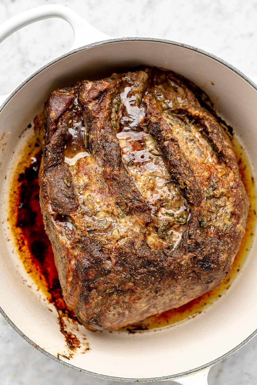 Cooked prime rib roast in a white dutch oven.