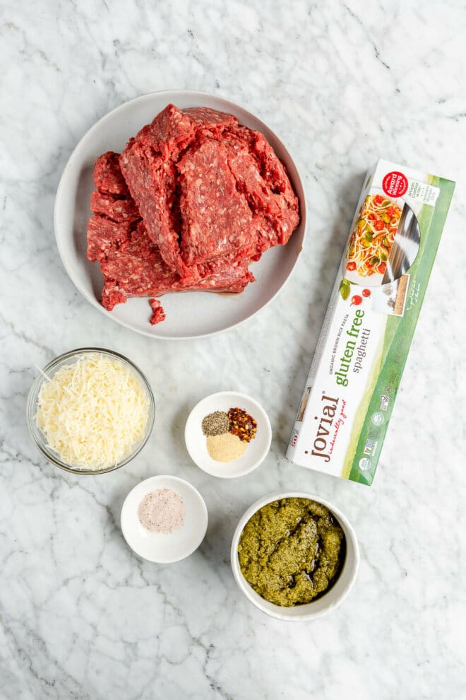 pesto meatball ingredients on a grey and white marble surface. 