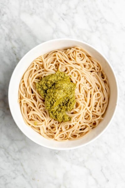 Scoop of pesto on top of a bowl of spaghetti.
