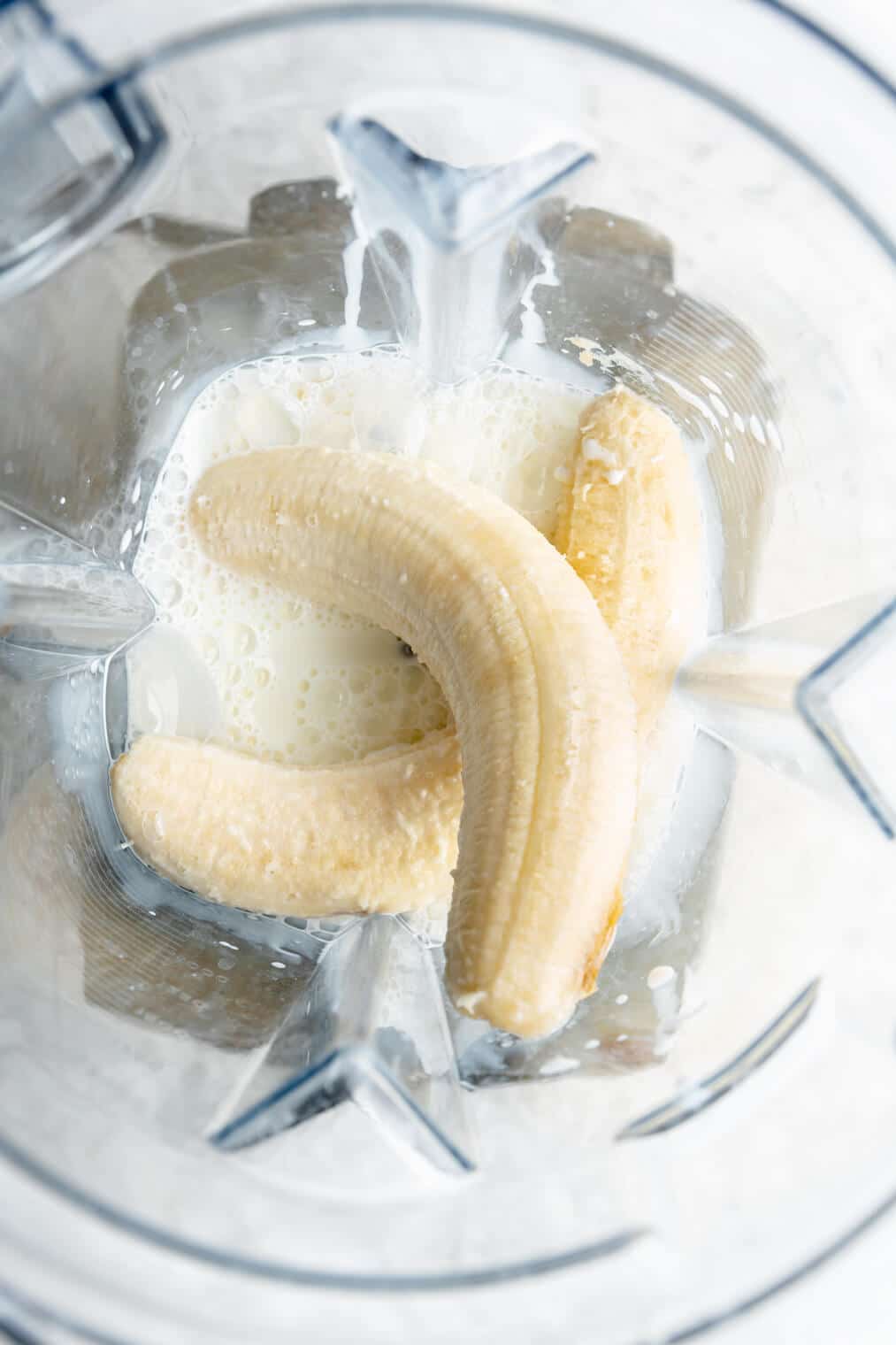 Two bananas and milk in a blender.