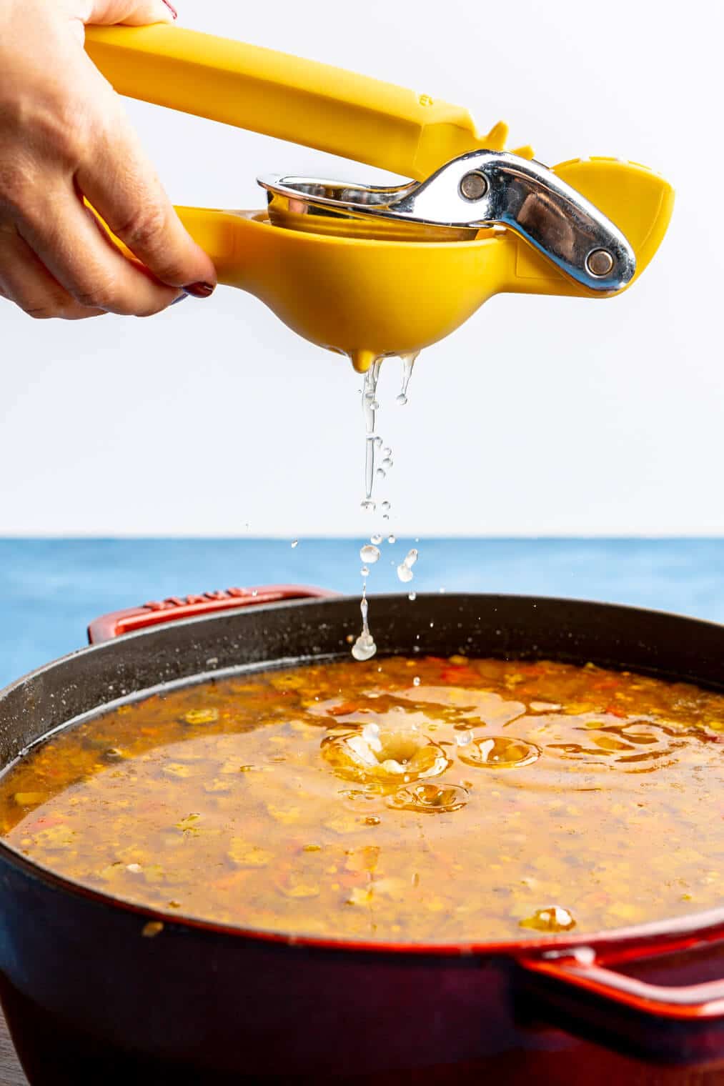 Lemon juice being squeezed over top a pot of gumbo.