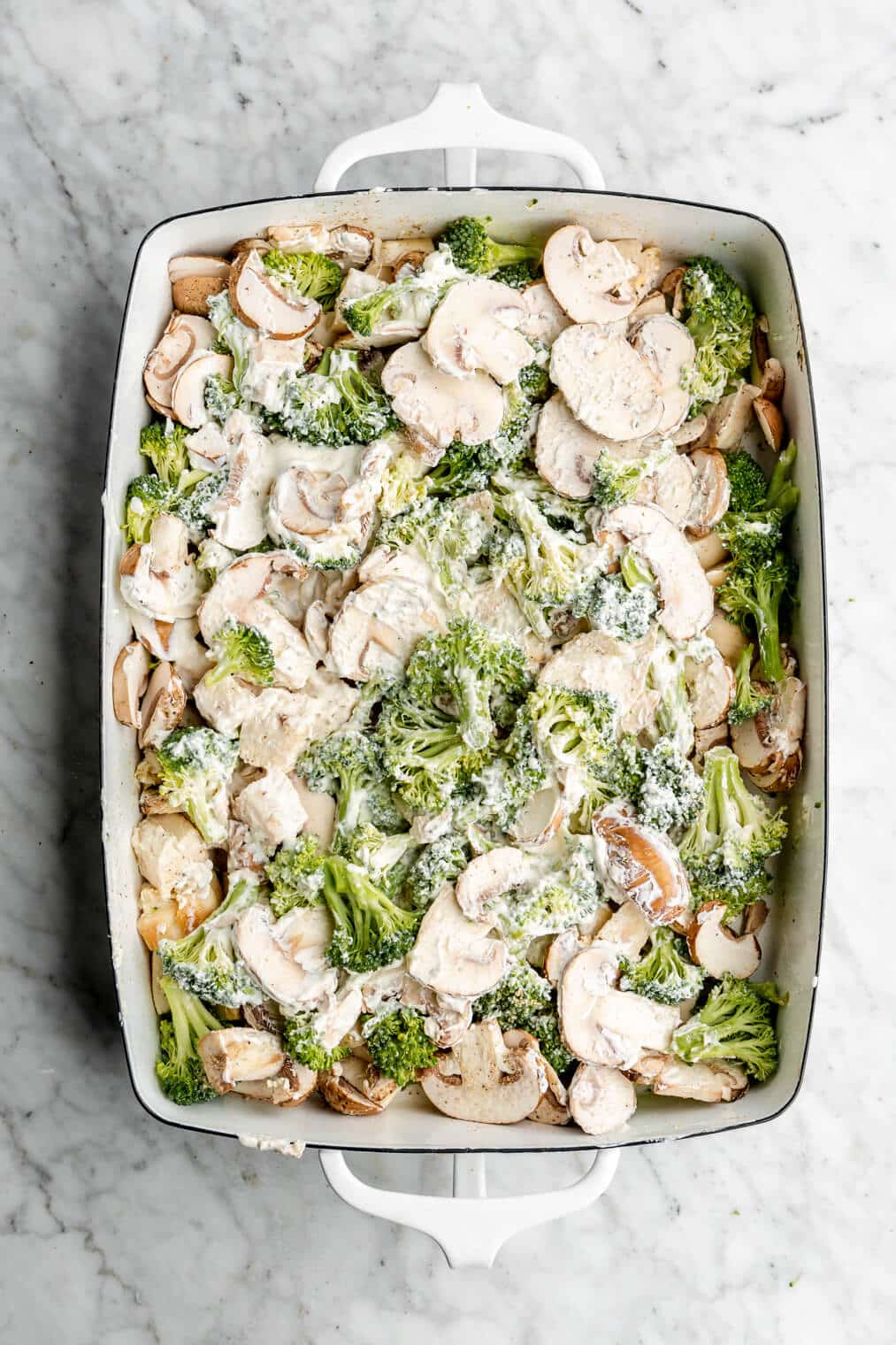 Mushrooms, broccoli, and chicken combined with sour cream in a casserole dish.