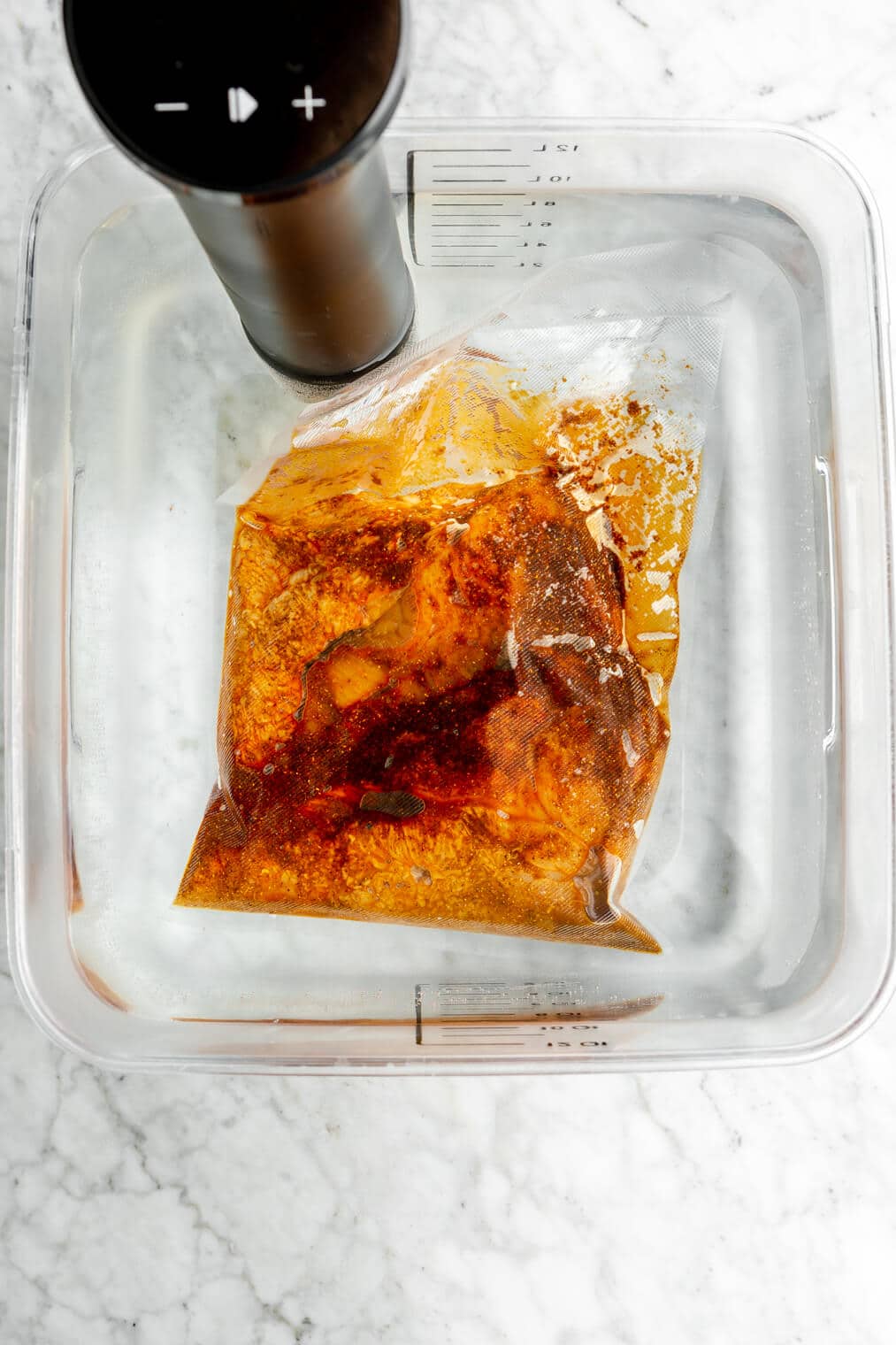 Sous vide chicken submerged in water with a sous vide device.