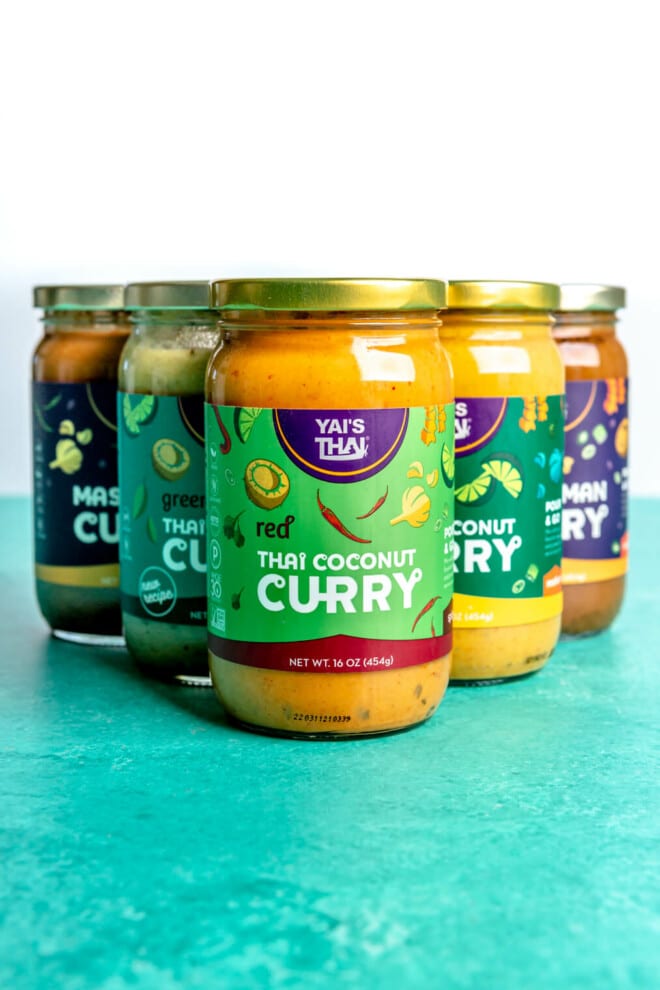 Yai's Thai curry sauces in a triangle formation on a teal surface.