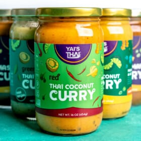Yai's Thai curry sauces in a triangle formation on a teal surface.