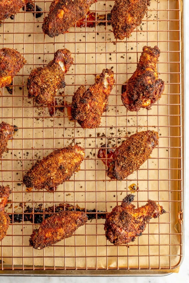 Baked dry rub chicken wings on a sheet pan lined with parchment paper. 