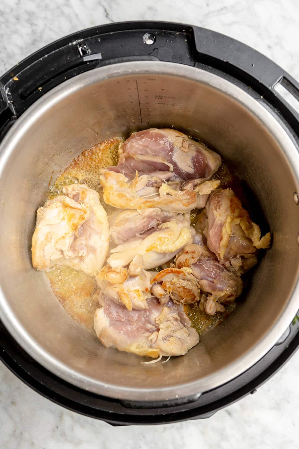 Raw chicken in an instant pot on saute mode.