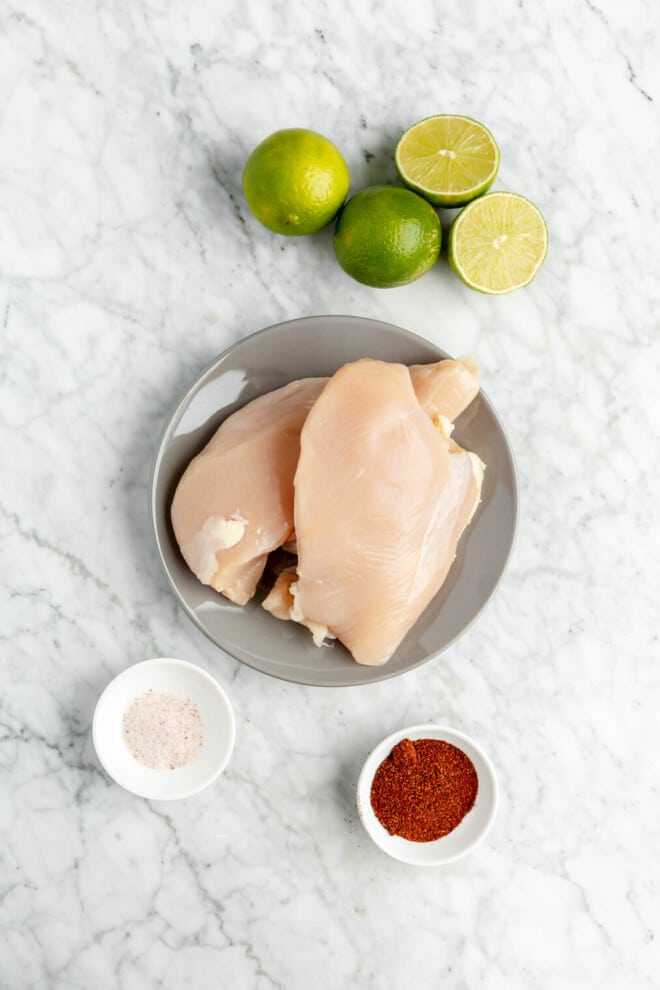 Mexican chicken marinade ingredients on a grey and white marble surface. 