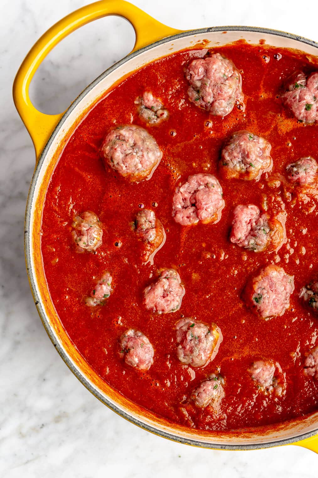 Yellow dutch oven filled with meatballs.