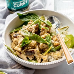 Bowl of green Thai coconut curry with chicken, eggplant, and snow peas.