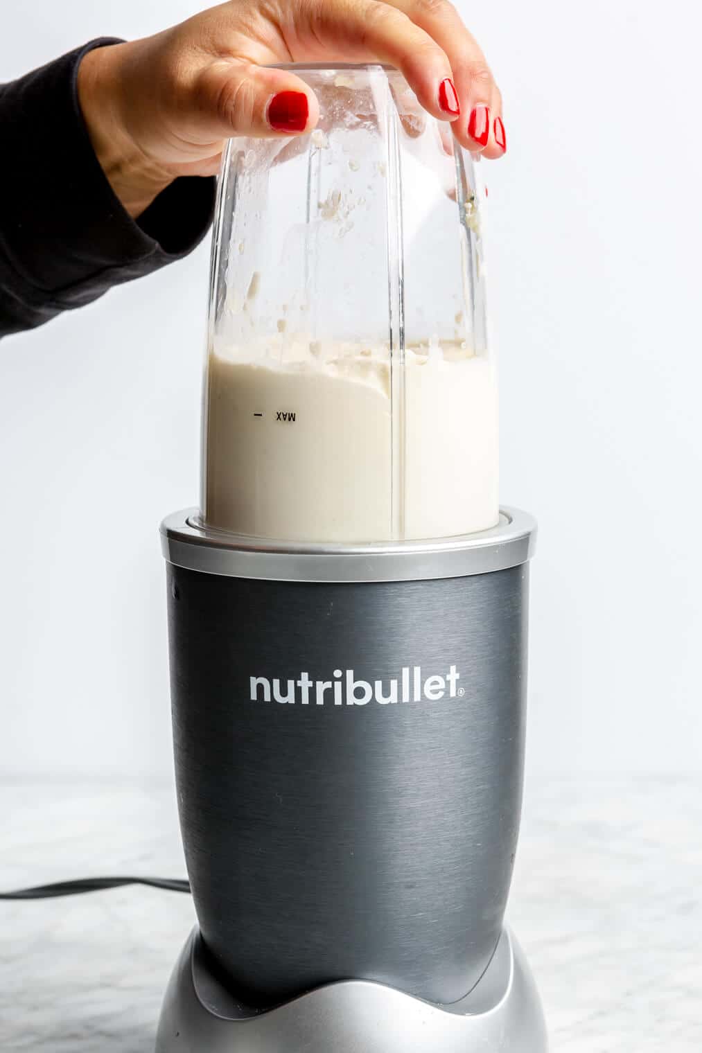 Hand holding down the blender container of a nutribullet.