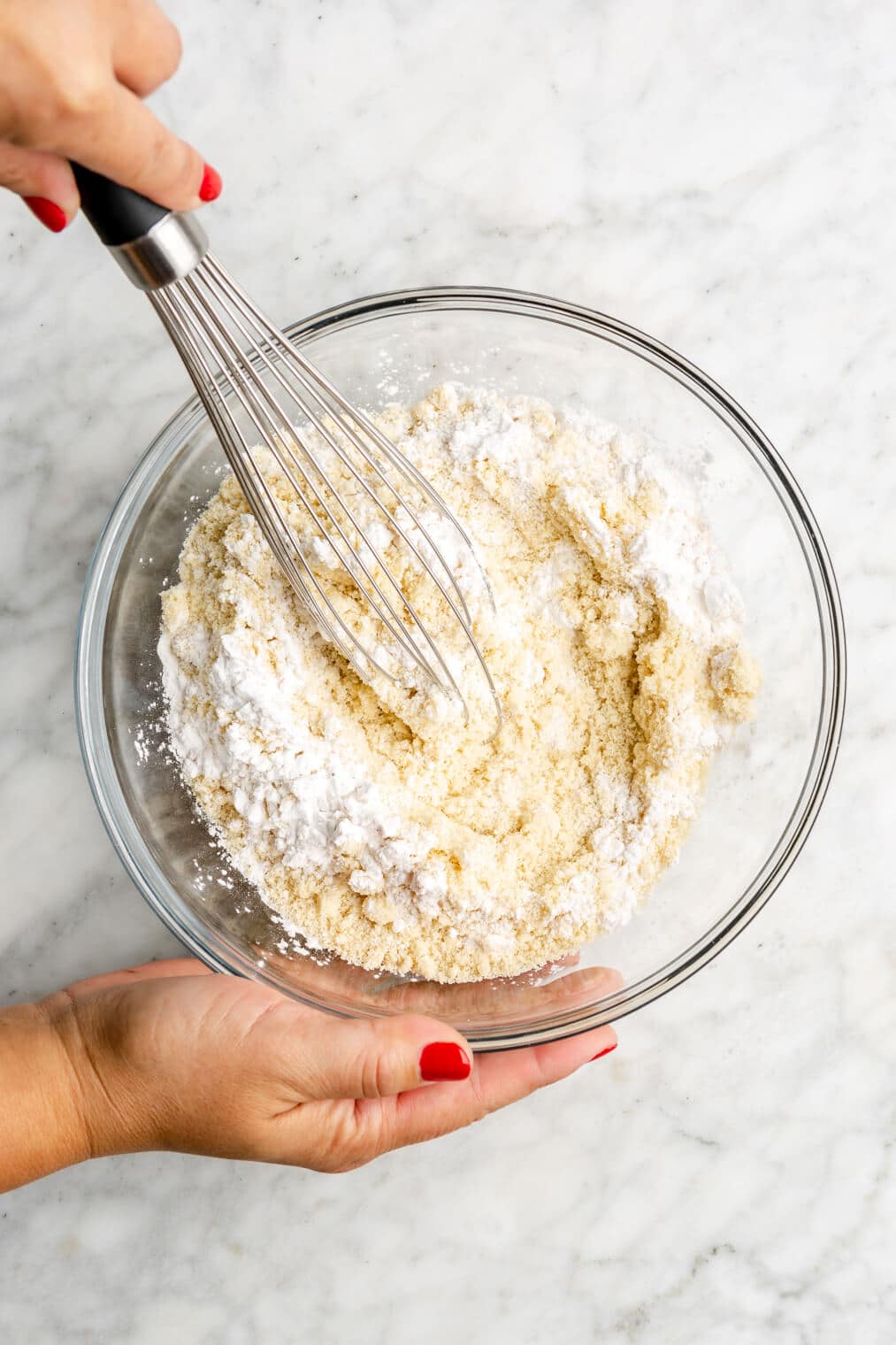 Dry ingredients being whisked together in a glass bowl.