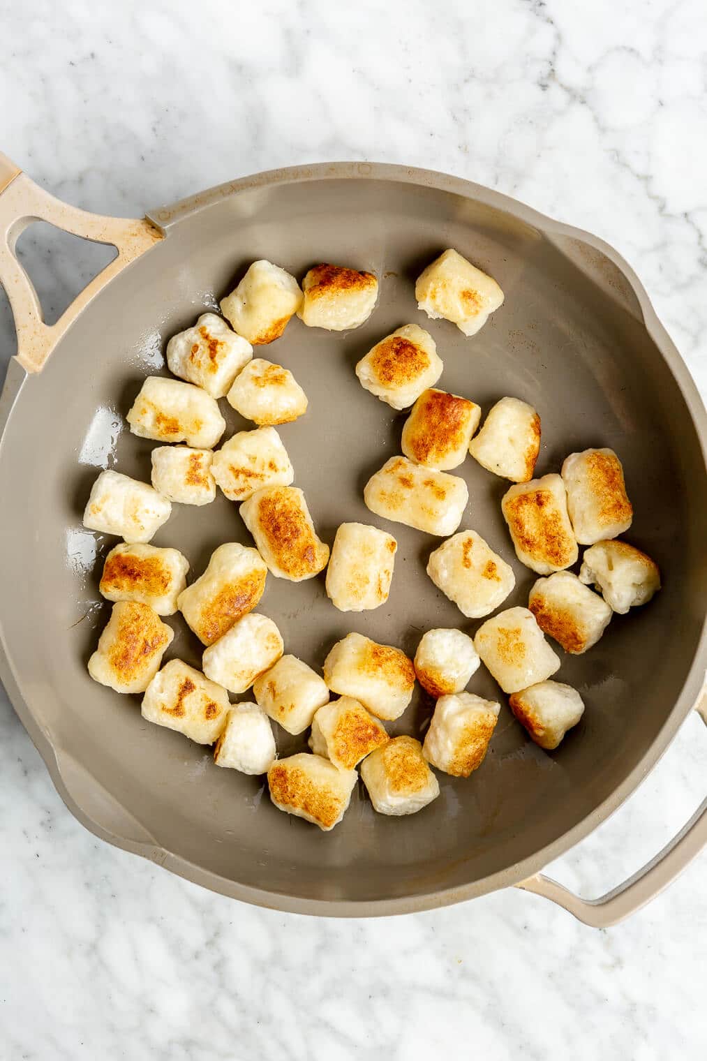 Browned gnocchi in a pan.