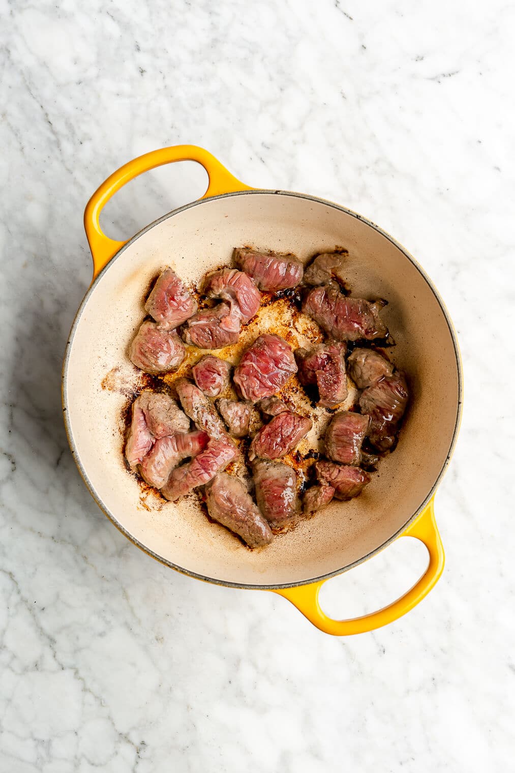 Stew meat searing in a large cast iron enameled pot.