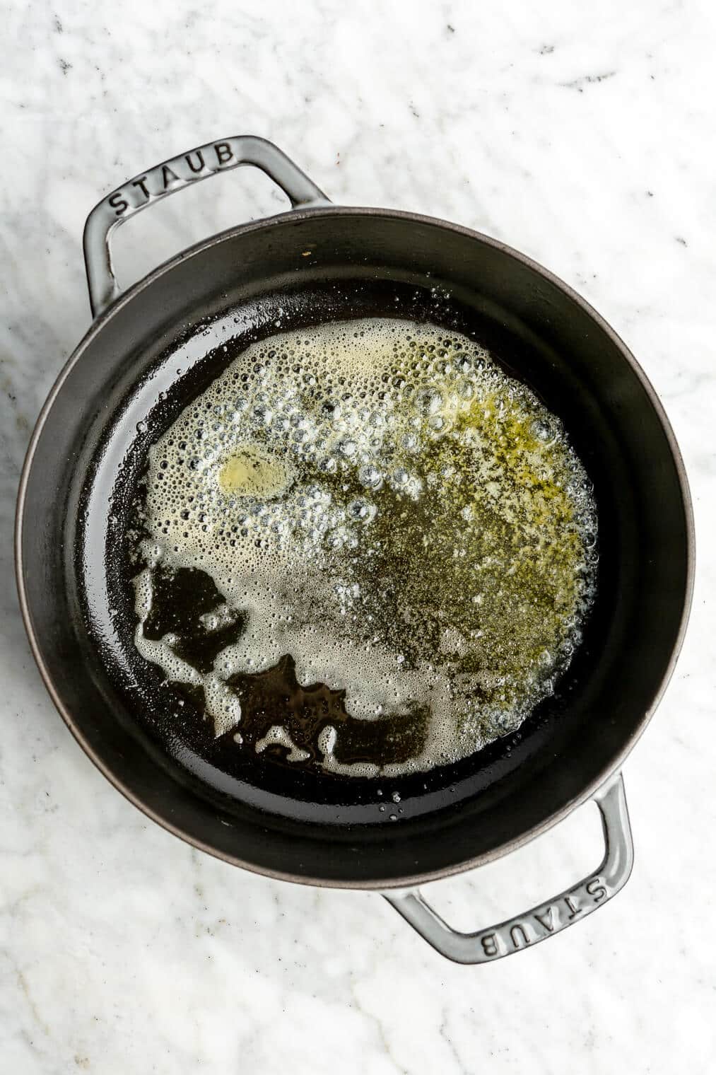 A cast iron dish with melted butter in it.