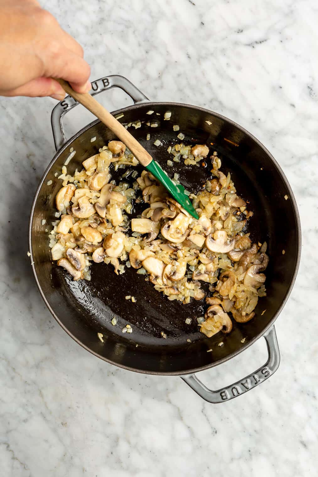 Someone sautéing mushrooms, garlic, and onions in a cast iron pan.