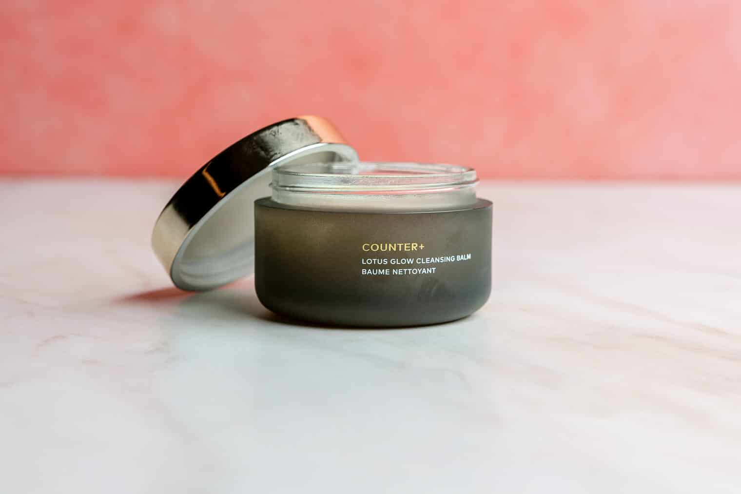 An open jar of Beautycounter's cleansing balm sitting on a marble surface.