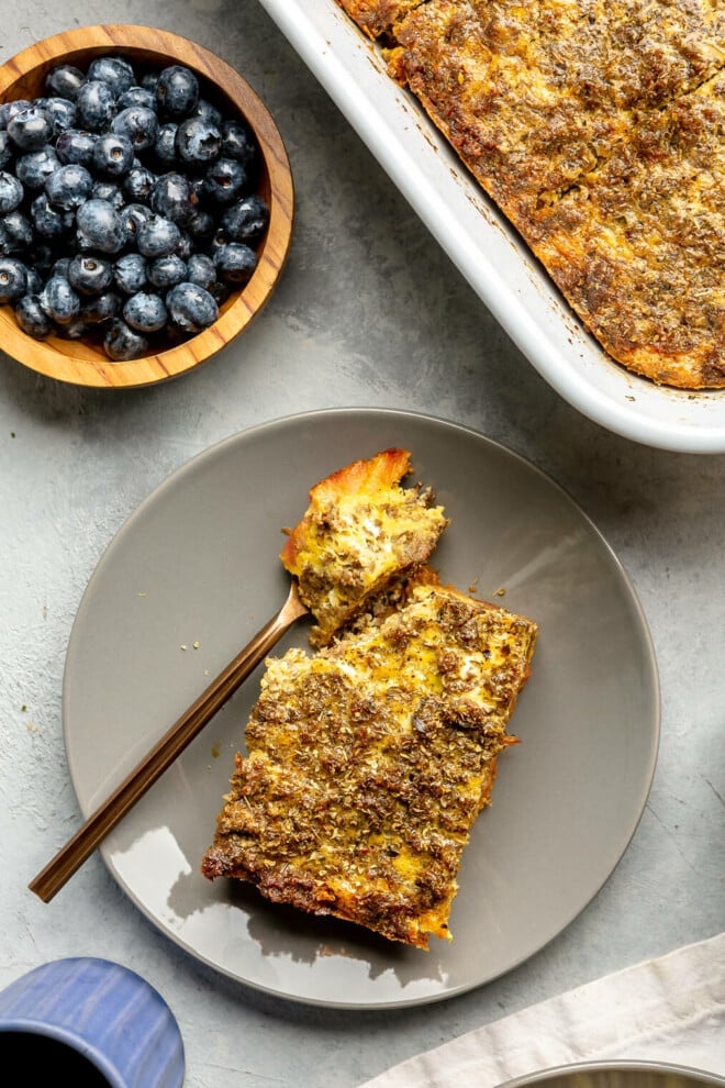 A slice of plantain breakfast casserole on a plate with a bite of it sitting on a fork.