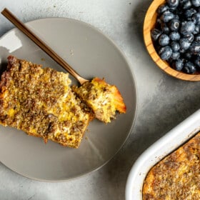 A slice of plantain breakfast casserole on a plate with a bite of it sitting on a fork.
