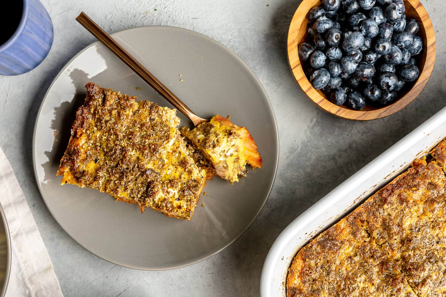 A slice of plantain breakfast casserole on a plate with a bite of it sitting on a fork.