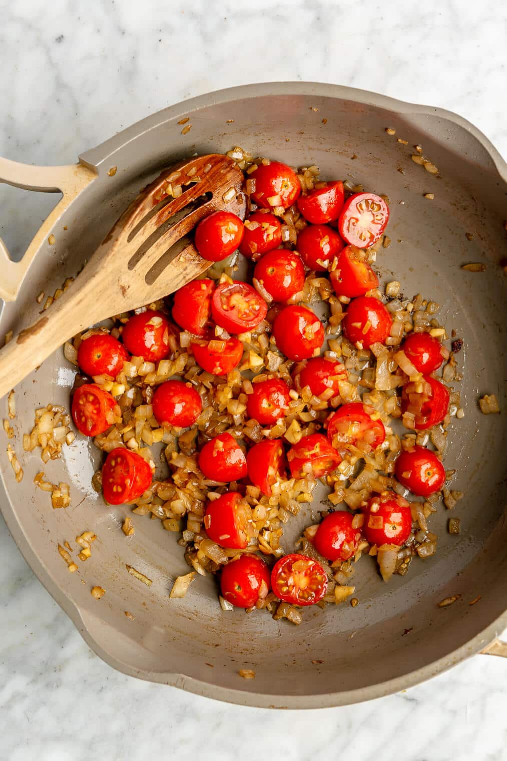 A pan of sauteed cherry tomatoes and onion.