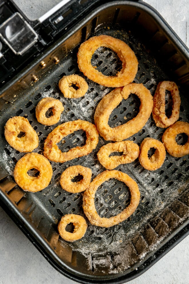 Cooked calamari rings in an air fryer basket.