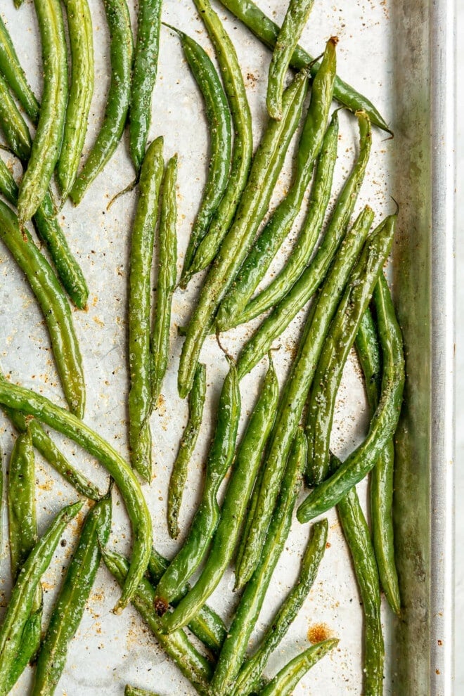 A close up of oven roasted green beans on a sheet pan.