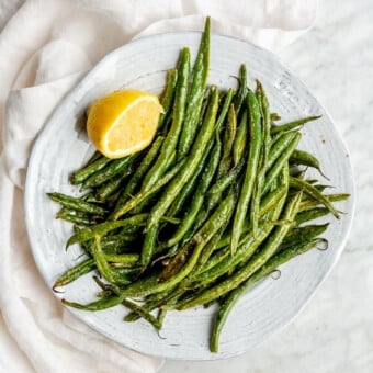 A white bowl filled with oven roasted green beans.